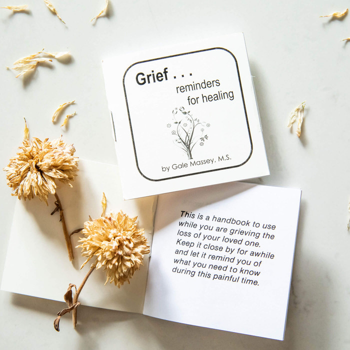 Small book laying on table with dried flowers with messages displayed