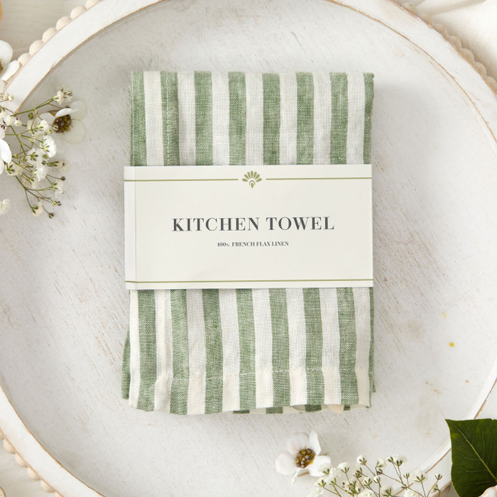 Green striped kitchen towel with a "Kitchen Towel" Tag surrounded by beige scenery and flowers