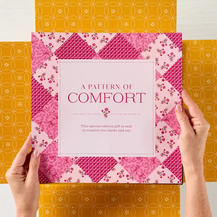 Overhead view of a Spoonful of Comfort gift featuring soup, rolls, cookies, a pink floral blanket, matching pouch, ladle, and “A Pattern of Comfort” gift packaging.