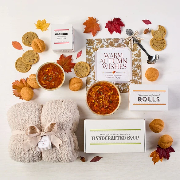 Overhead image displaying "Warm Autumn Wishes" card, Spoonful of Comfort Box, styled with soups, rolls and cookies.