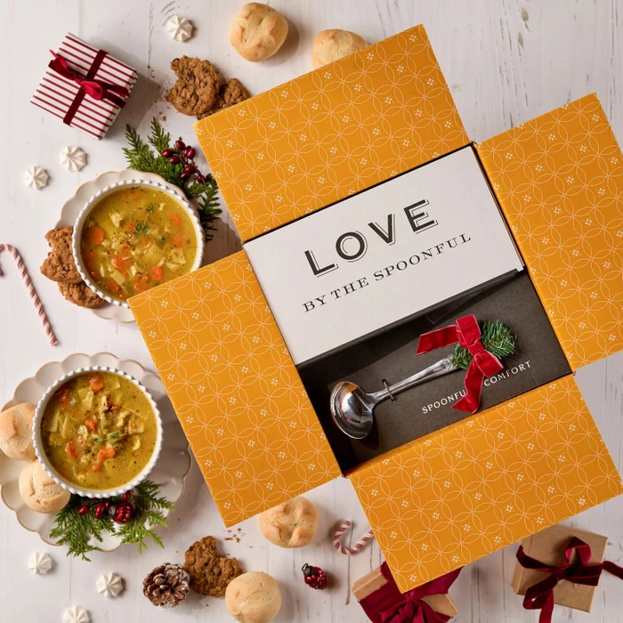 Decorative soup package with two bowls of soup, holiday decorations and a ladle with a bow