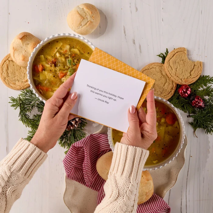 Note insert being held by two hands, soup displayed behind it.