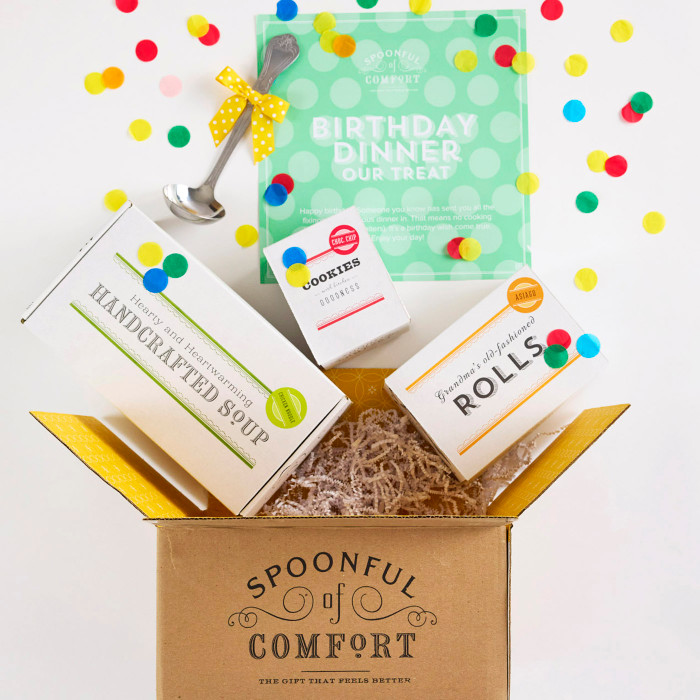 Open Spoonful of Comfort gift box filled with packaged rolls, a container of handcrafted soup, cookies, and a birthday card that reads “Birthday Dinner Our Treat,” with colorful confetti falling around the box.