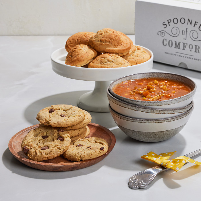 Bowl of vegan soup, vegan cookies and vegan rolls displayed on a table with a ladle and a box