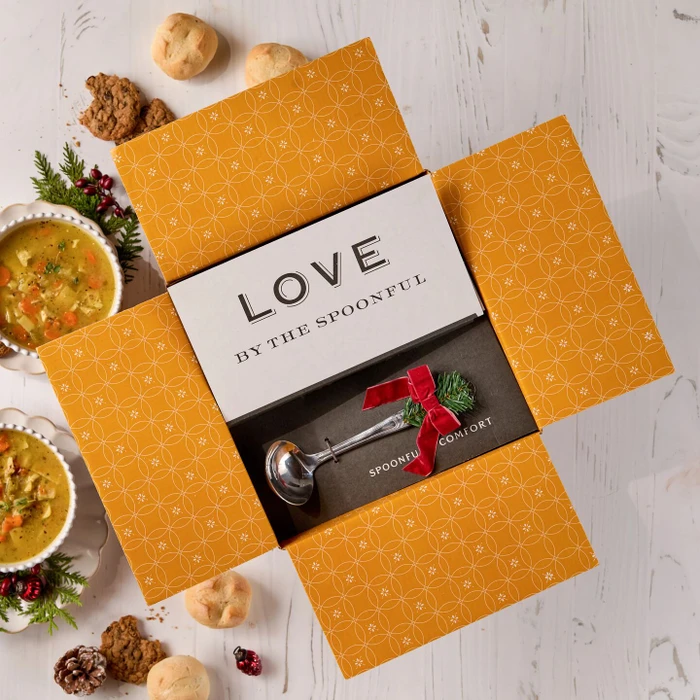 Decorative soup package with two bowls of soup, holiday decorations and a ladle with a bow