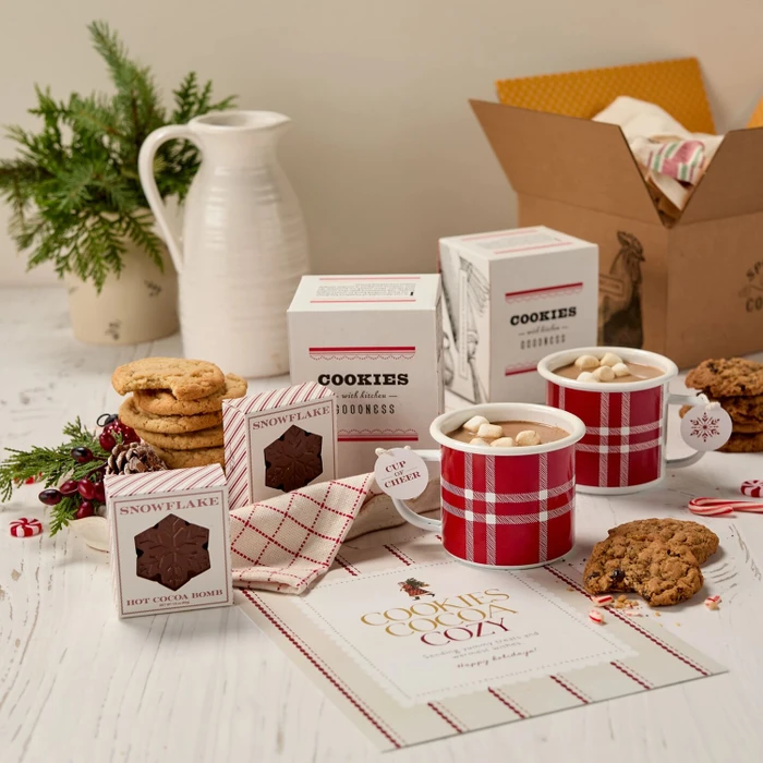 Festive Holiday Cookie Package with a decorative insert, and surrounded by cookie boxes and mugs.