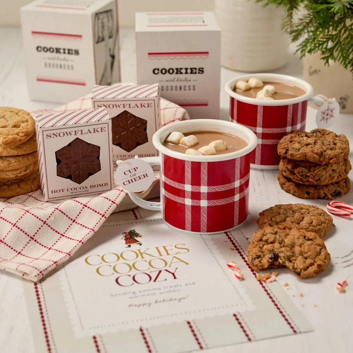 Festive Holiday Cookie Package with a decorative insert, and surrounded by cookie boxes and mugs.