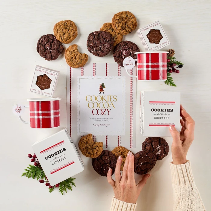 Festive Holiday Cookie Package with a decorative insert, and surrounded by cookie boxes and mugs.