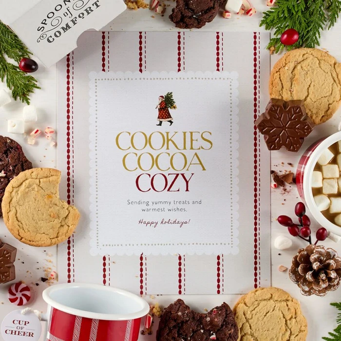 Festive Holiday Cookie Package with a decorative insert, and surrounded by cookie boxes and mugs.