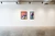 The Magnificence series paintings in the gallery. Two paintings in metal black frames hang on the white wall of a gallery. The floor is polished concrete, the ceiling is white.