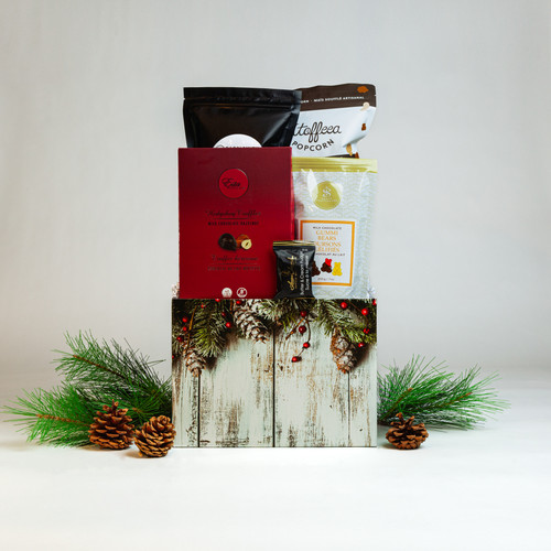 An entire basket brimming with delicious Made in Canada favourites featuring Chocolate Covered Gummi Bears, Esta Chocolates Hedgehog Truffle Box, and Bagelsmith Bagel Chips made locally right here in Winnipeg, and more. All wrapped up in a festive evergreen motif gift box and trimmed with a hand tied red ribbon.  