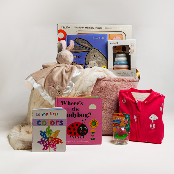 A pink toy storage bin full of baby items to celebrate the precious new arrival! A super soft, oh so cuddly snuggler, toys, board books and more! 