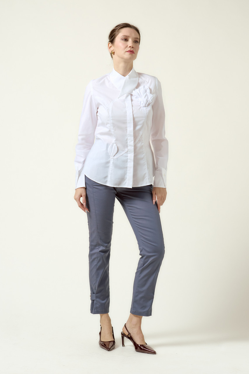 Model wearing the DALB Arcadia Bloom white shirt with a 3D flower appliqué, architectural collar, and grey tailored trousers against a neutral background.
