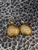Handcrafted hammered gold-plated disc earrings with moissanite, photographed against a textured black and white background.