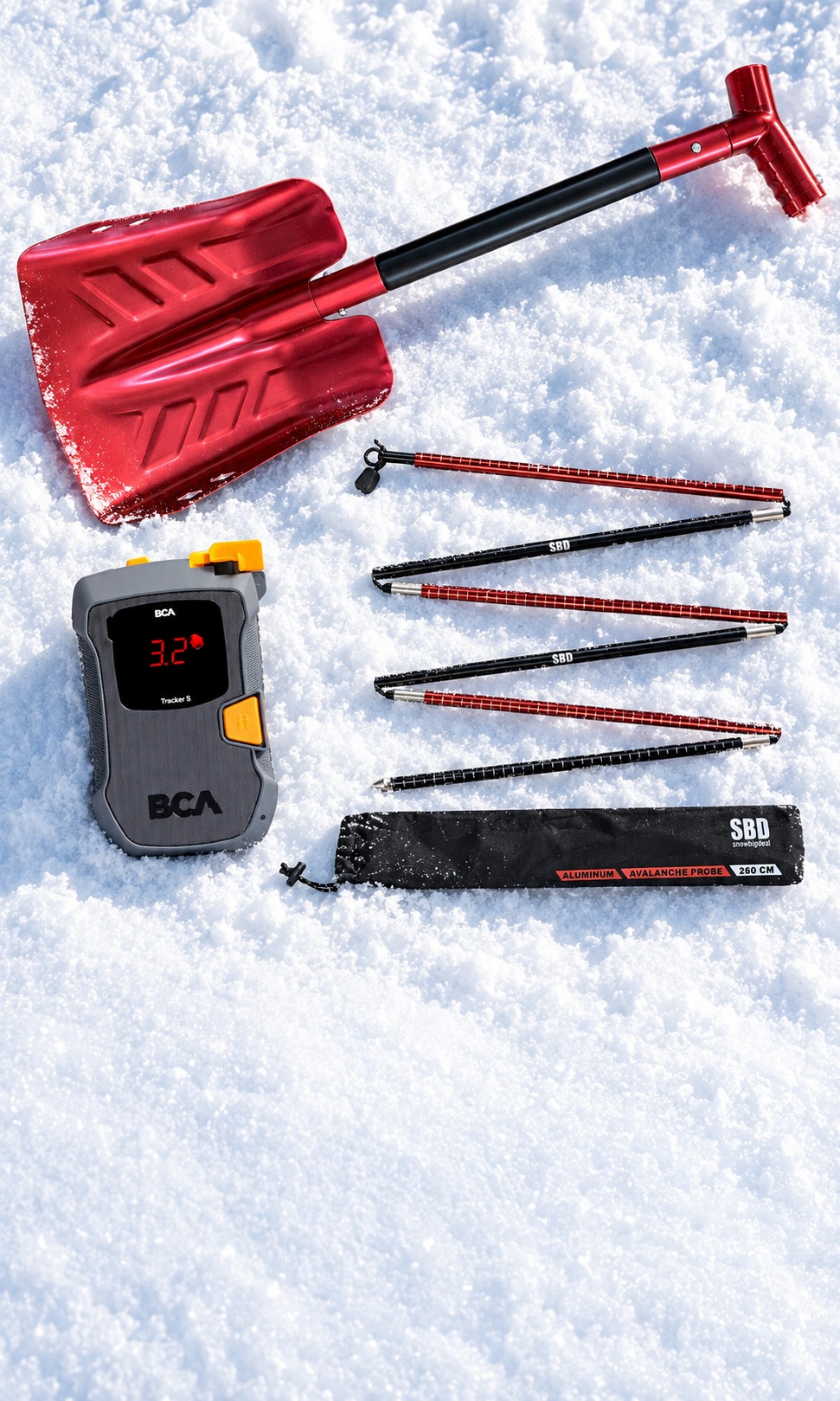 Avalanche rescue bundle with a red shovel, BCA Tracker S beacon and folded probe arranged on snow