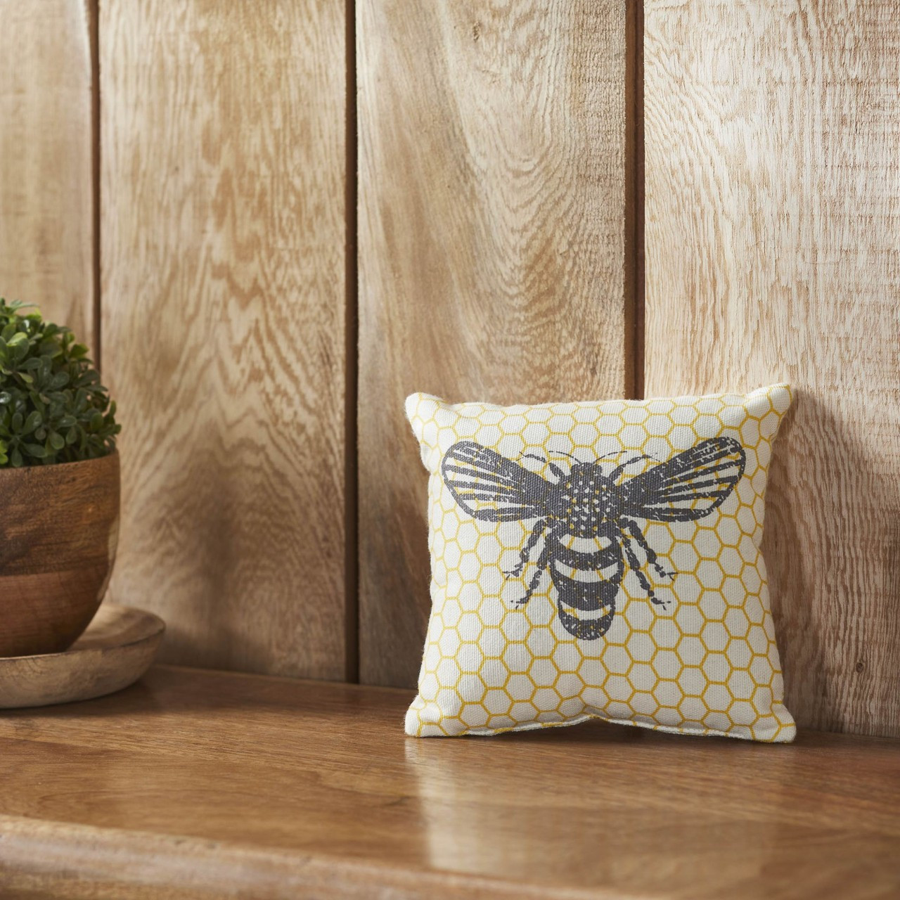 Buzzy bees throw pillow on a wooden bench