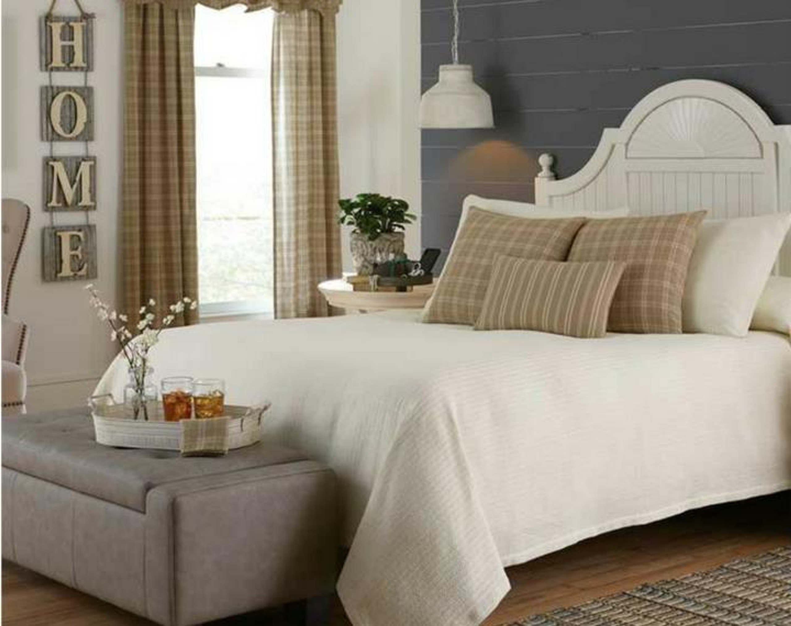 A bed with sleek cream bedding and plaid pillows