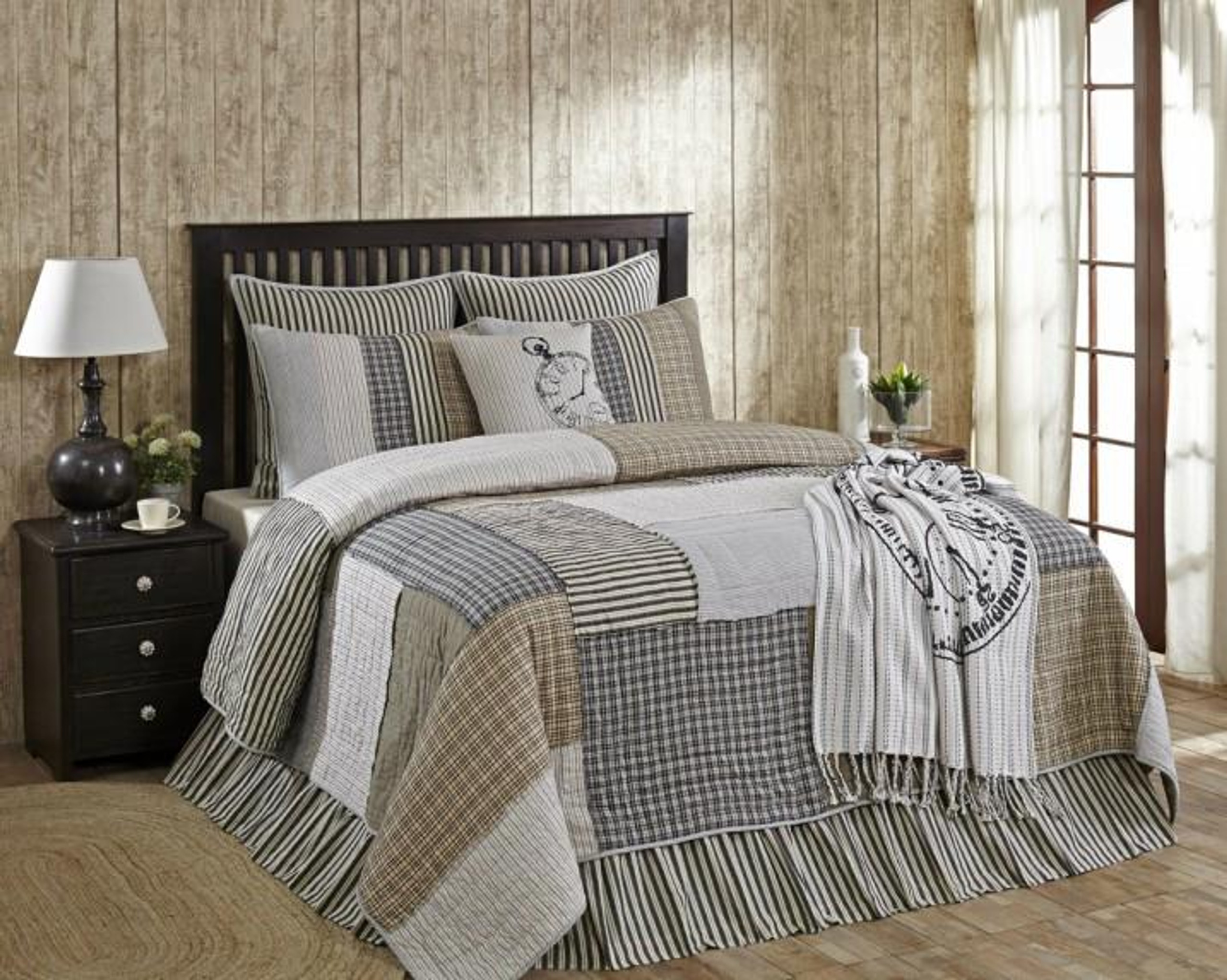 Bed with black and cream patchwork bedding in between 2 side tables