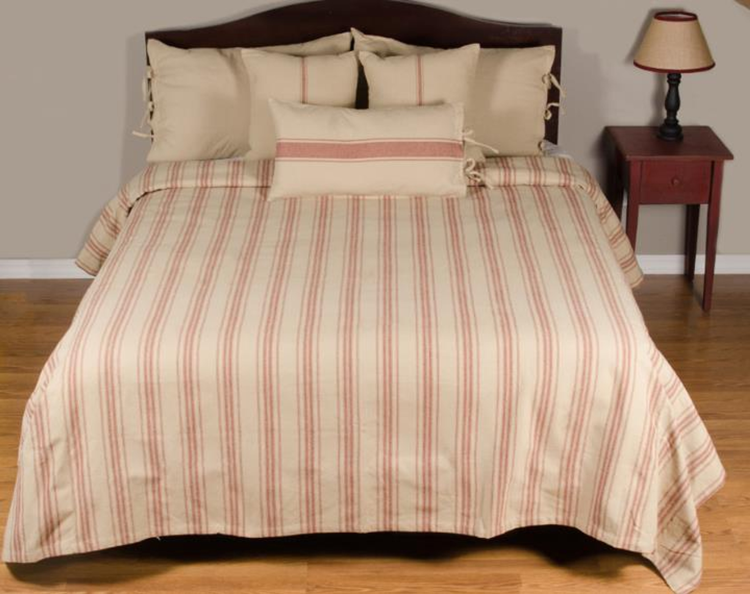 Bed with barn red grain striped bedding next to a small side table