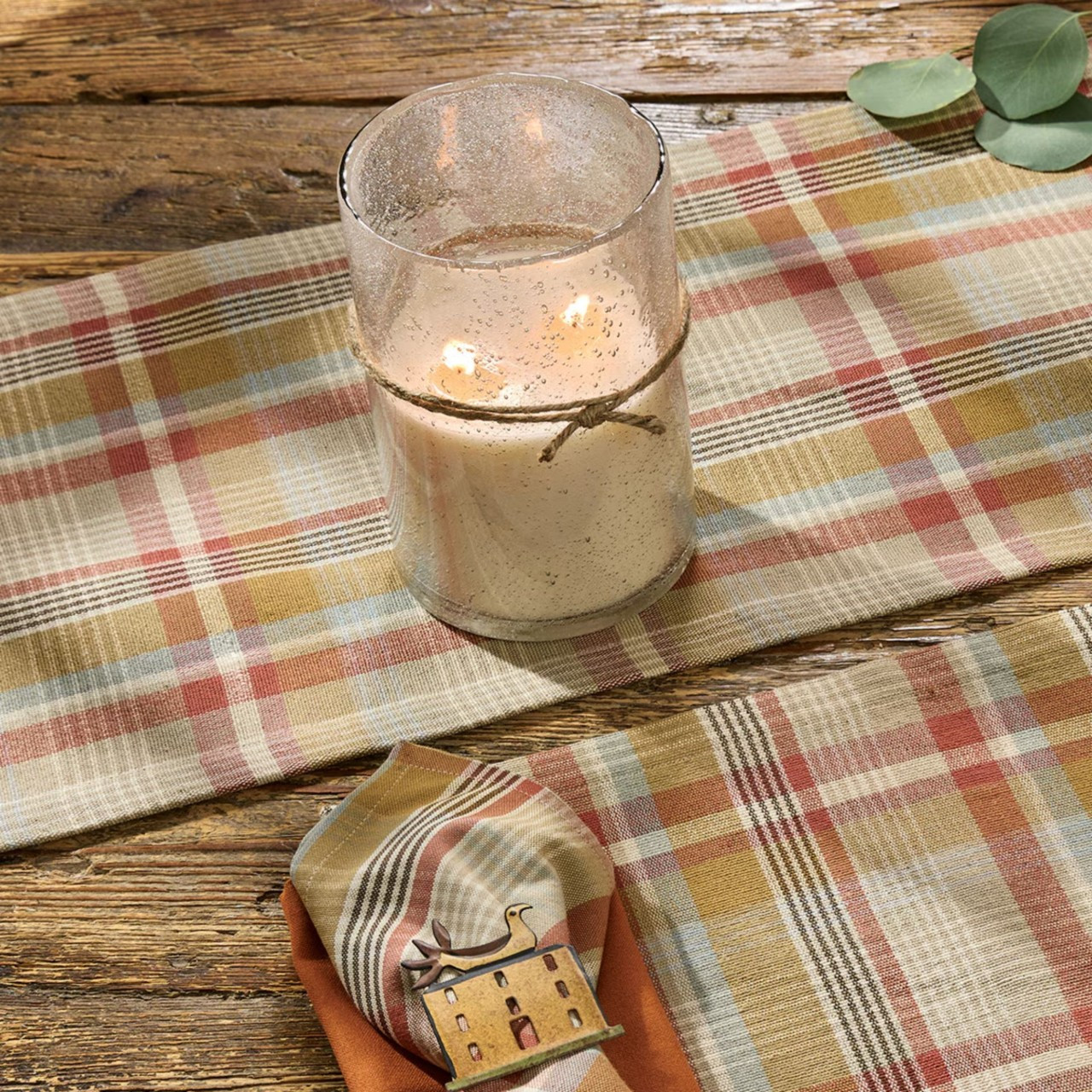 Lit candle over a light plaid table runner