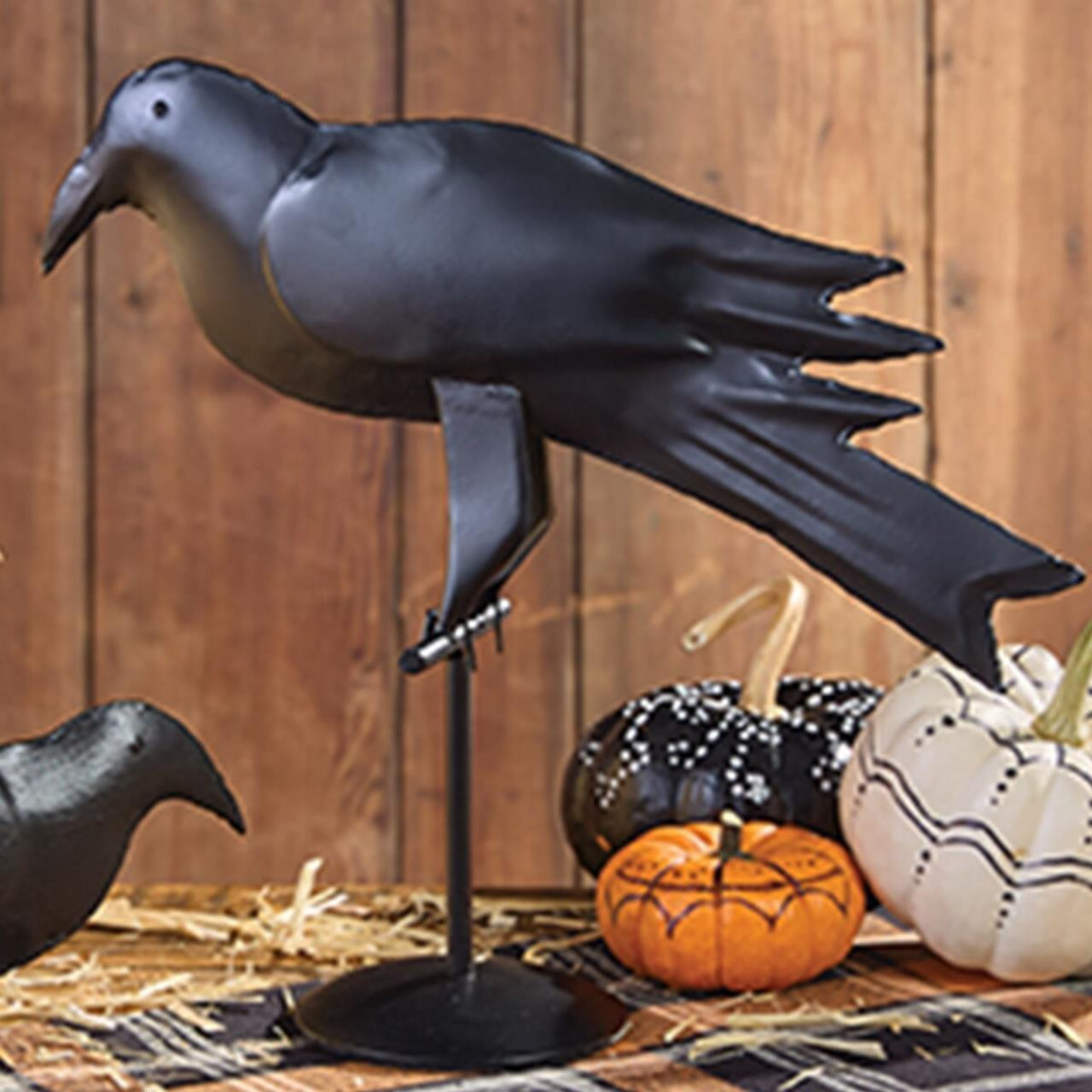 Primitive iron crow on a table next to pumpkins