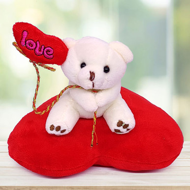 Cream Teddy Bear Sitting on a Red Heart Pillow