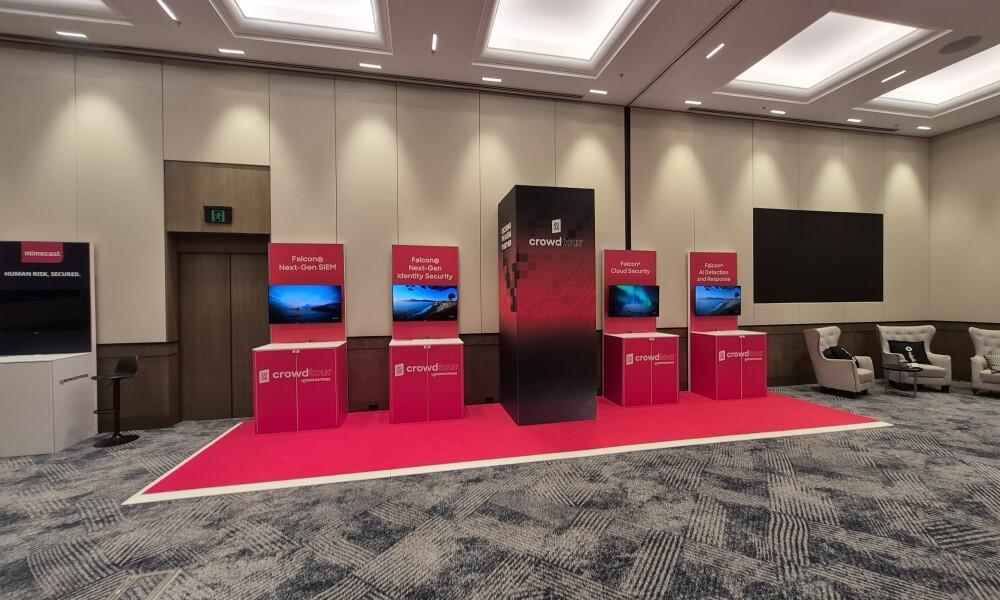 Corporate technology event fit-out with branded demo pods, screens, red carpet and feature lighting
