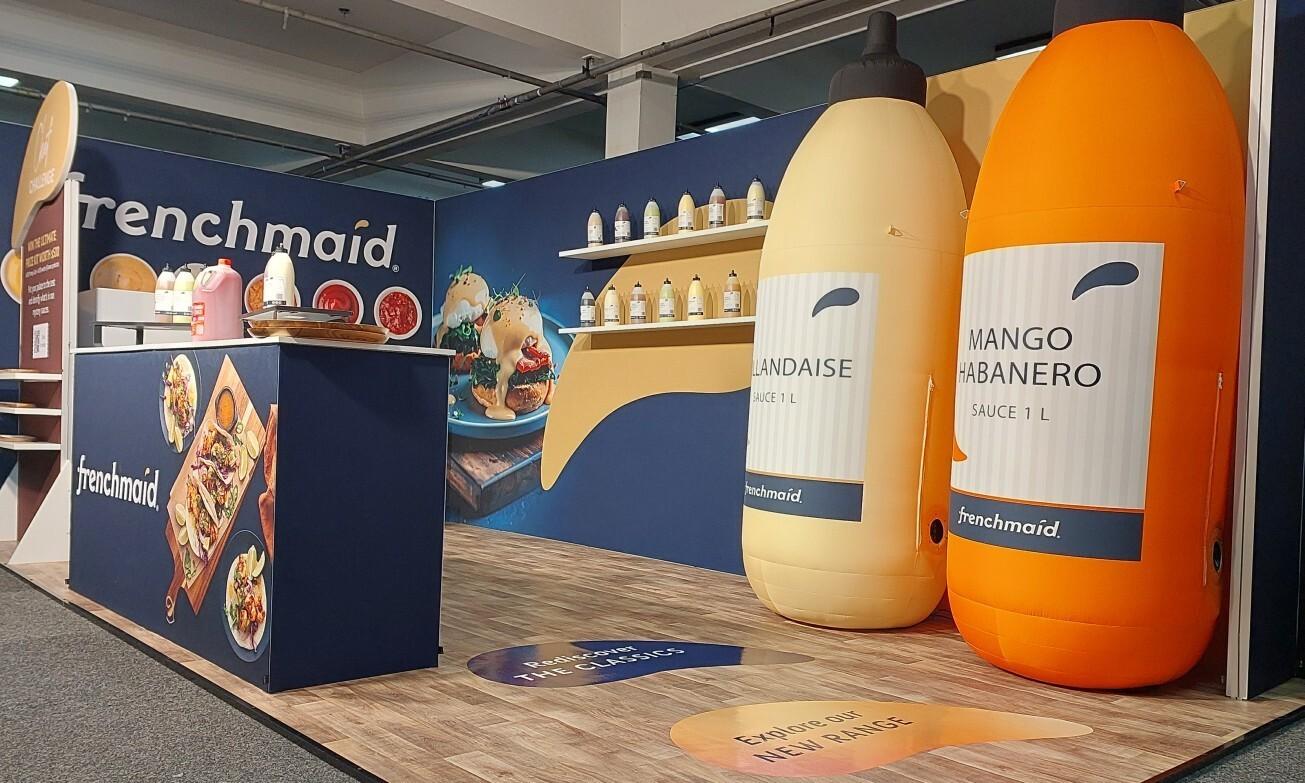 Side view of Frenchmaid trade show stand with inflatable product bottles