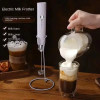 Woman using USB milk frother to create foam in a glass mug of oat milk on a kitchen countertop Woman using USB milk frother to create foam in a glass mug of oat milk on a kitchen countertop