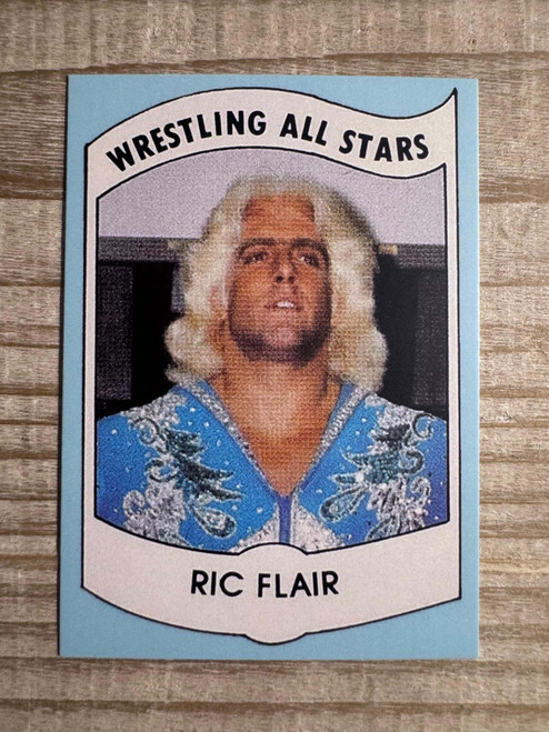 Reissued 1982 Ric Flair Wrestling All Stars #27 trading card shown in a clear protective sleeve, featuring The Nature Boy in a classic red robe pose, positioned against a clean white background for display