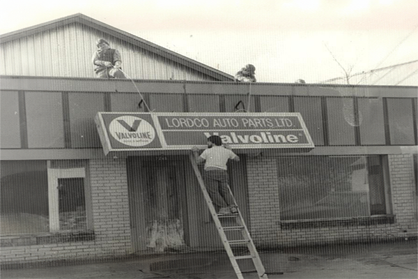 Sign being pulled up by store manager D'Arcy Giberson and partsman Jay Graboski