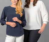 A navy top with shirred cuffs and a white blouse displayed on two women against a grey background. A navy top with shirred cuffs and a white blouse displayed on two women against a grey background.