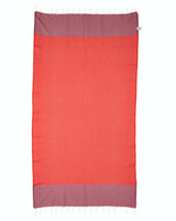 A Redsands beach towel in vibrant red and purple, featuring decorative tassels along the edges and a subtle texture.