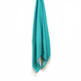 A turquoise beach towel with a textured pattern and fringed edges, hanging on a white background. A turquoise beach towel with a textured pattern and fringed edges, hanging on a white background.