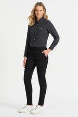 A woman wearing a black chino pant paired with a dark shirt and white sneakers. The outfit features a logo. A woman wearing a black chino pant paired with a dark shirt and white sneakers. The outfit features a logo.