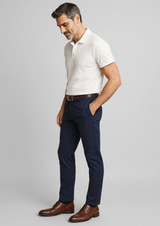 A man in a beige polo shirt and dark navy chino pants stands, wearing brown shoes and a belt. A man in a beige polo shirt and dark navy chino pants stands, wearing brown shoes and a belt.