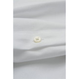 A black button on a folded black shirt, showcasing the fabric texture and stitching details. The shirt has a logo.