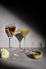 A set of three elegant glasses on a grey surface, featuring a stemmed wine glass, a martini glass, and a stemless wine glass.
