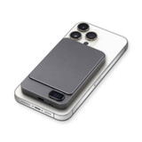 A grey magnetic wireless power bank sits on a smartphone, featuring a sleek design and a logo.