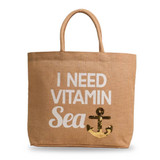 A jute bag in natural colour featuring sequin details and a design with the text "I Need Vitamin Sea" and an anchor.