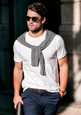 A white men's T-shirt with a grey sweater casually draped around the shoulders, paired with dark trousers and sunglasses.