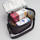 A black cooler bag with a silver insulated interior, holding snacks and a drink carton inside.