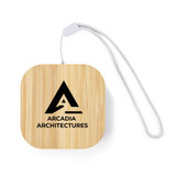 A square bamboo cable organiser with a silver strap, featuring a black logo on the front.