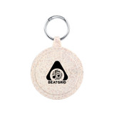 A round, speckled beige keychain with a metal ring and a logo featuring a triangle and musical notes. A round, speckled beige keychain with a metal ring and a logo featuring a triangle and musical notes.