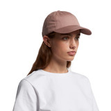 A pink cap with a rounded peak, featuring a logo on the side. The model wears a white t-shirt.