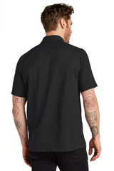 A black polo shirt featuring short sleeves, shown from the back on a model with tattoos. It has a logo on the collar.