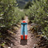 A drink bottle in turquoise and orange positioned on a dirt path surrounded by greenery, featuring a logo.
