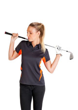A woman in a dark grey polo shirt with orange accents holds a golf club, wearing a white glove.