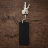 A black rectangular keychain attached to several metal keys on a wooden surface.