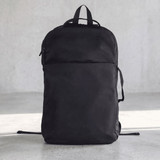 A black backpack with a sleek design and a front pocket, featuring straps and a logo on the side.